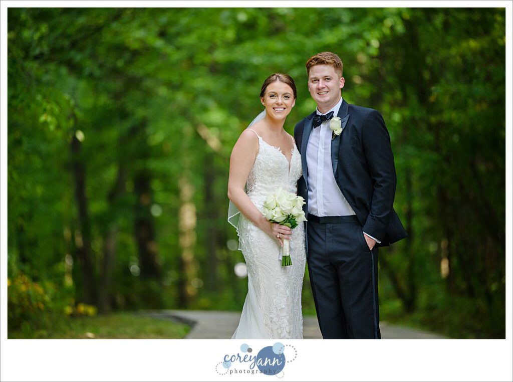Bride and groom posing in September at Huntington Reservation in Cleveland in a forested lane in Ohio