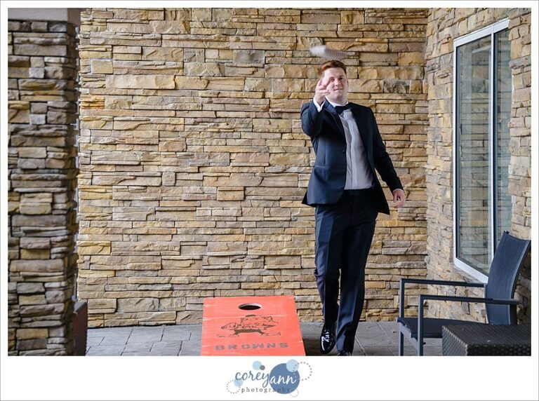 Groomsman playing cornhole before wedding in Avon in Ohio