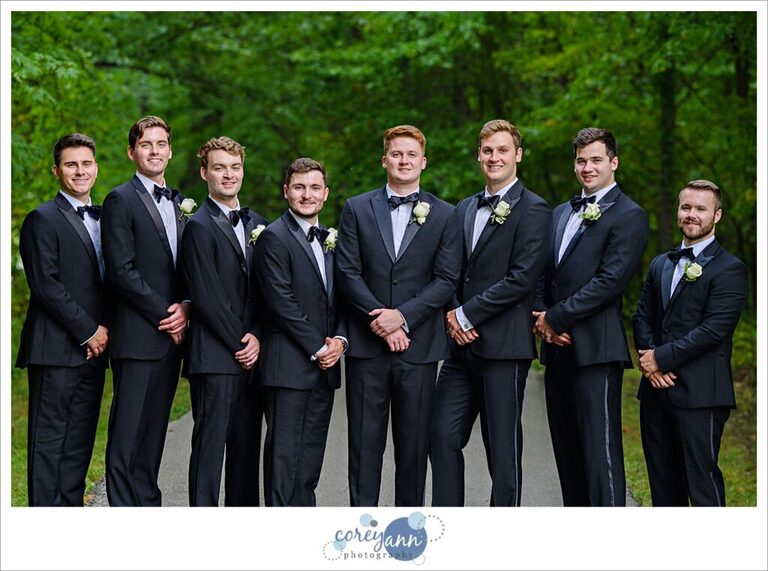 Groom and Groomsman wearing black tuxes pose for photos at Huntington Reservation in Ohio