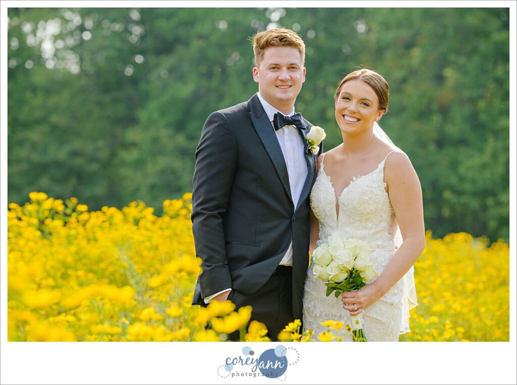 Bride and groom posing in yellow wildflower field at Huntington Reservation in Ohio