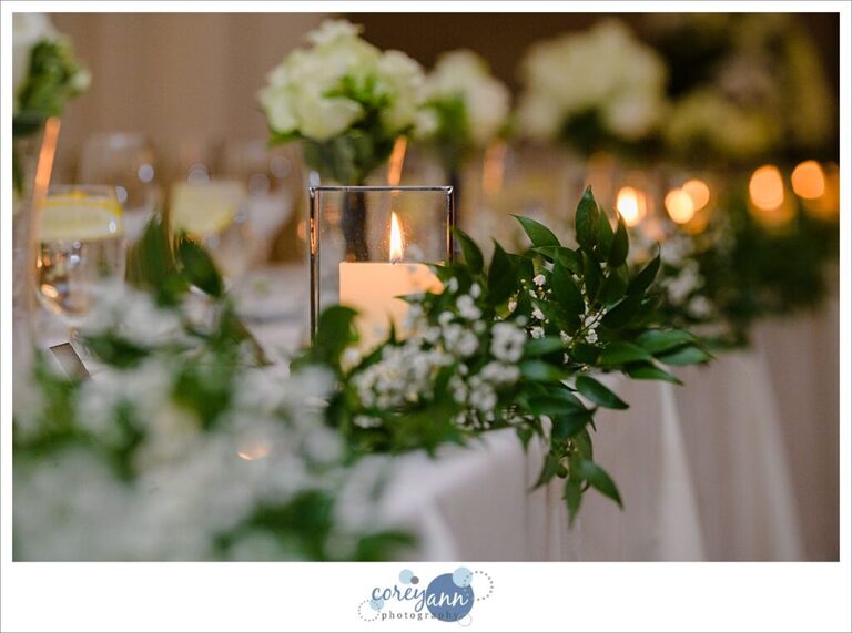 Candle nestled into garland decorating the head table at a wedding reception at Emerald Event Center in Avon Ohio