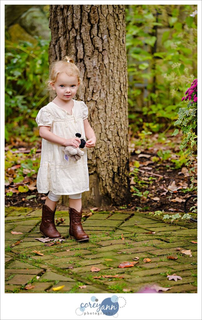 Small child running around during a wedding ceremony wearing cowboy boots and a light pink dress