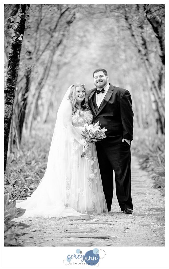 Classic black and white wedding portrait of a bride and groom wearing traditional attire in the birch tree allee at Stan Hywet Hall and Gardens after their ceremony in Akron Ohio