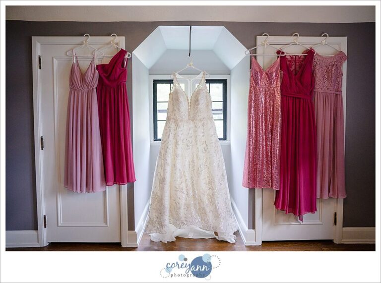 Bride's dress hanging with pink bridesmaids dresses at Tudor House on Portage Lakes in Akron