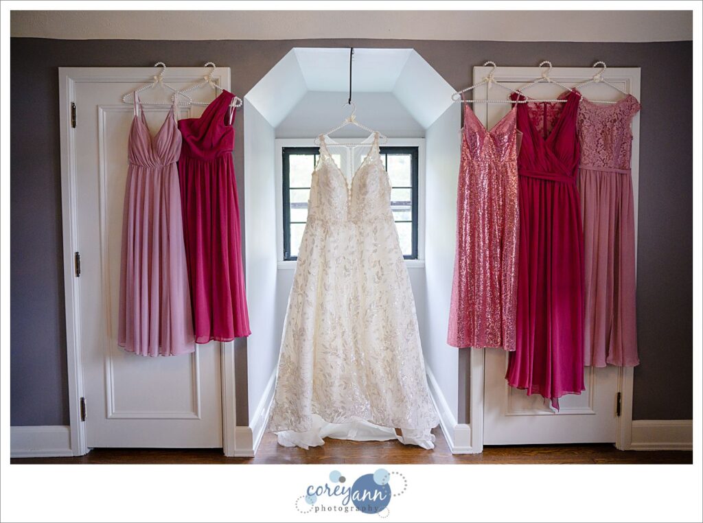 Bride's dress hanging with pink bridesmaids dresses at Tudor House on Portage Lakes in Akron