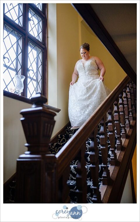 Bride walking down stairs at the Tudor House on Portage Lakes before her wedding 