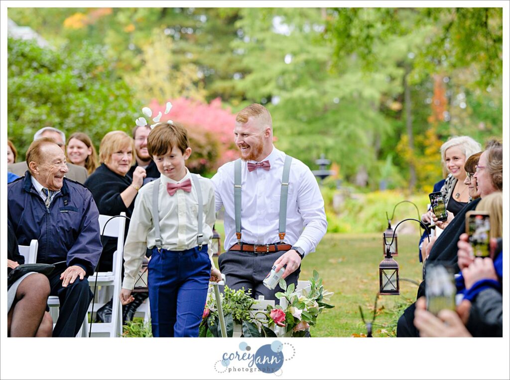 Ring bearer pulling beer boy in a wagon for wedding ceremony at tudor house on portage lakes