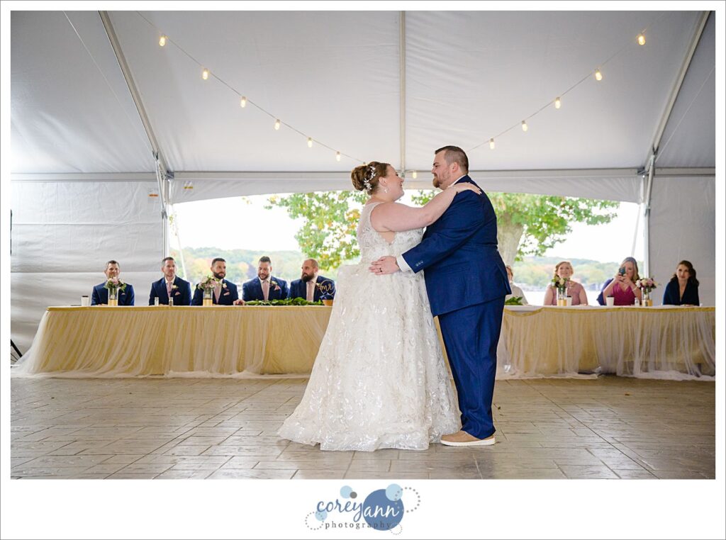 Bride and groom first dance beneath tent on lakefront at Tudor House on Portage Lakes in Akron Ohio