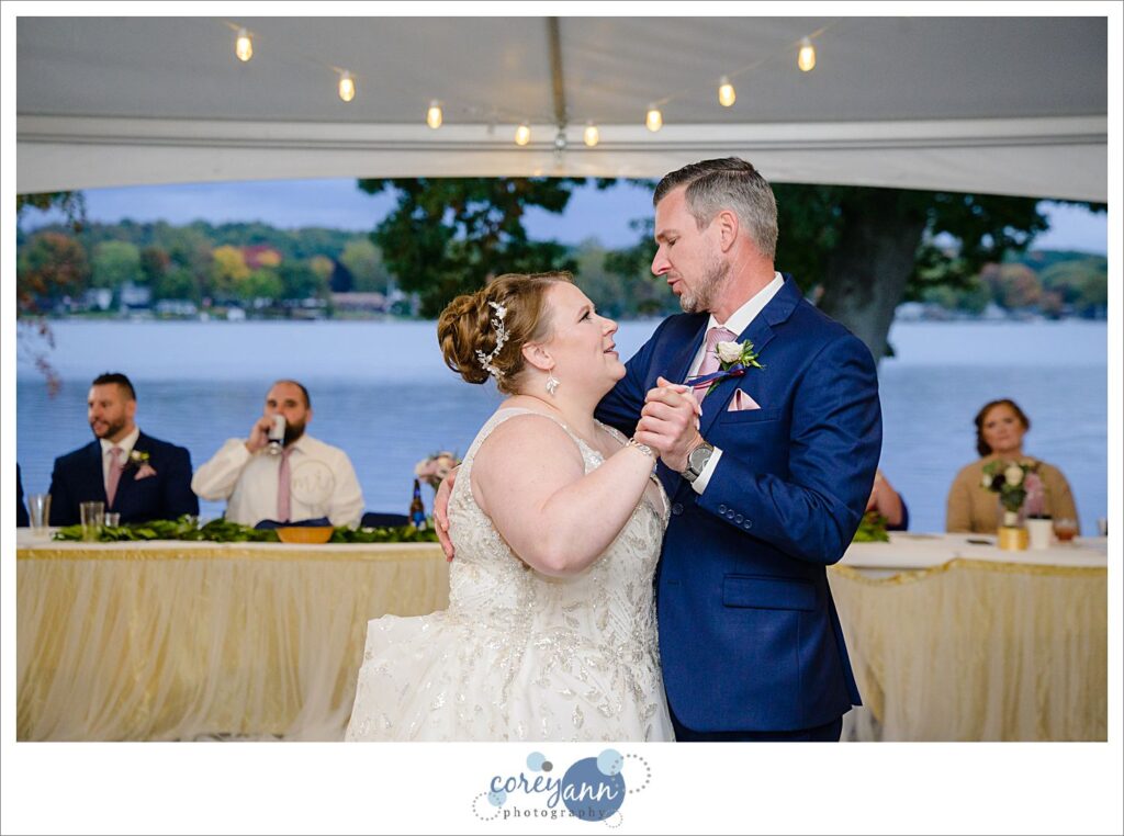 Bride and brother dance during wedding reception beneath the tent at Tudor House on Portage Lakes