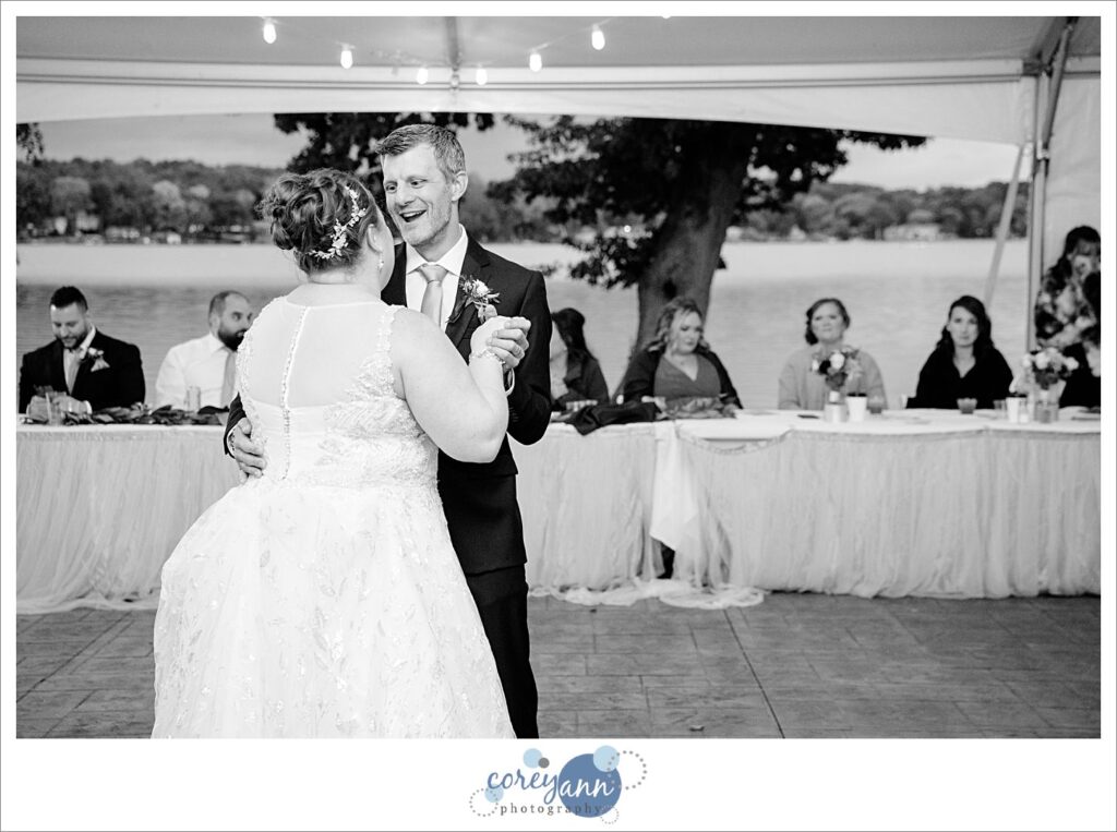 Bride and brother dance during wedding reception beneath the tent at Tudor House on Portage Lakes