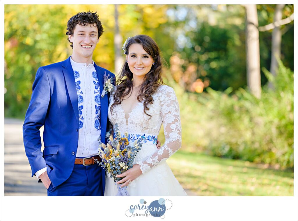 Bride and groom casually posing and smiling at the camera in front of autumn foliage at Garfield Park Reservation in Cleveland after a wedding