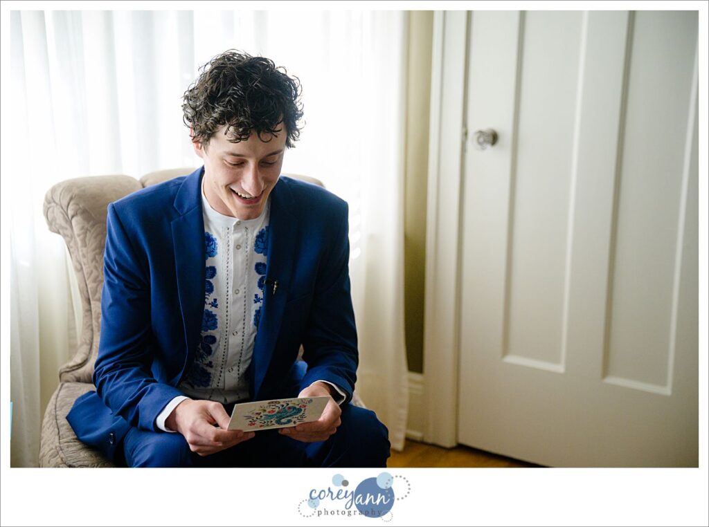 A man sits on a chair reading a letter from his bride before their wedding in Cleveland Ohio