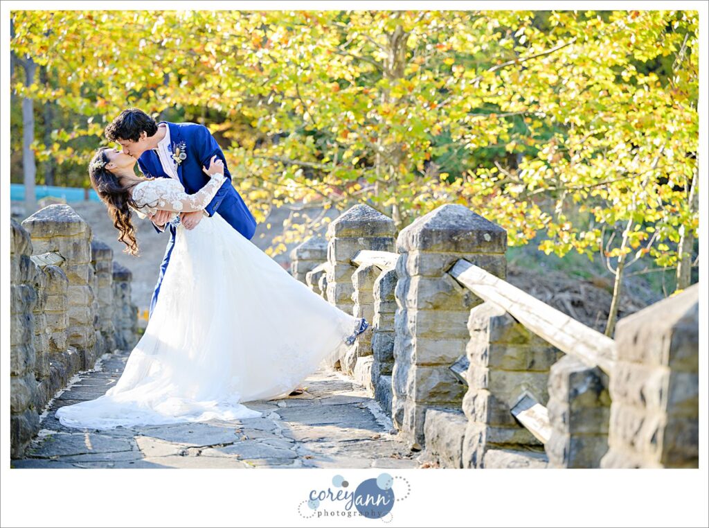 Groom dipping his bride on a bridge in Garfield Park Reservation after their wedding in Cleveland Ohio
