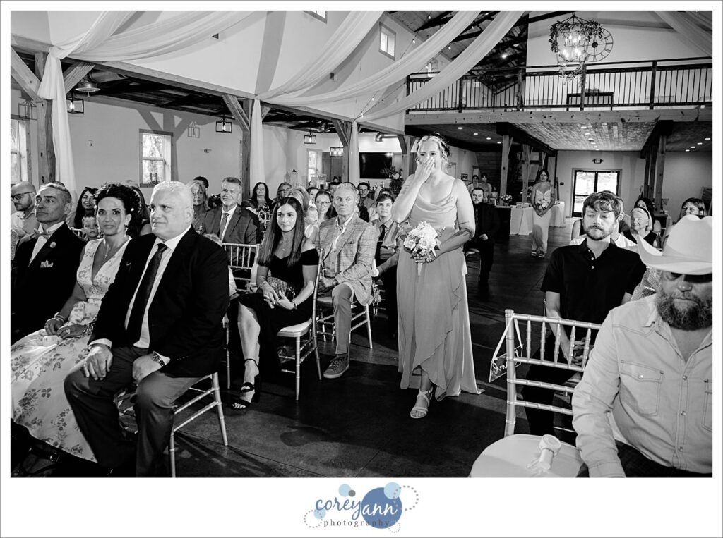 Bridesmaid tearing up when seeing groom waiting for bride to walk down the aisle 