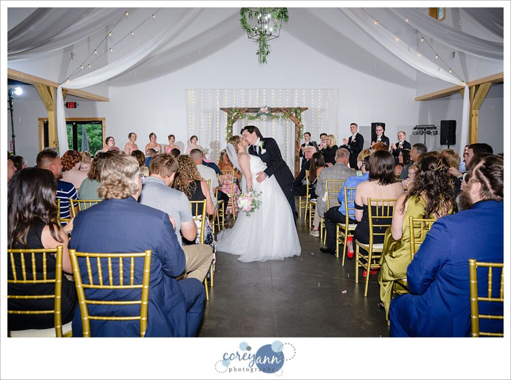 Bride and Groom kissing midway down the aisle after wedding ceremony at The Barn of Canal Fulton