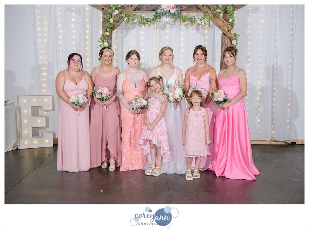 Bride with bridesmaids in various shades of pink dresses