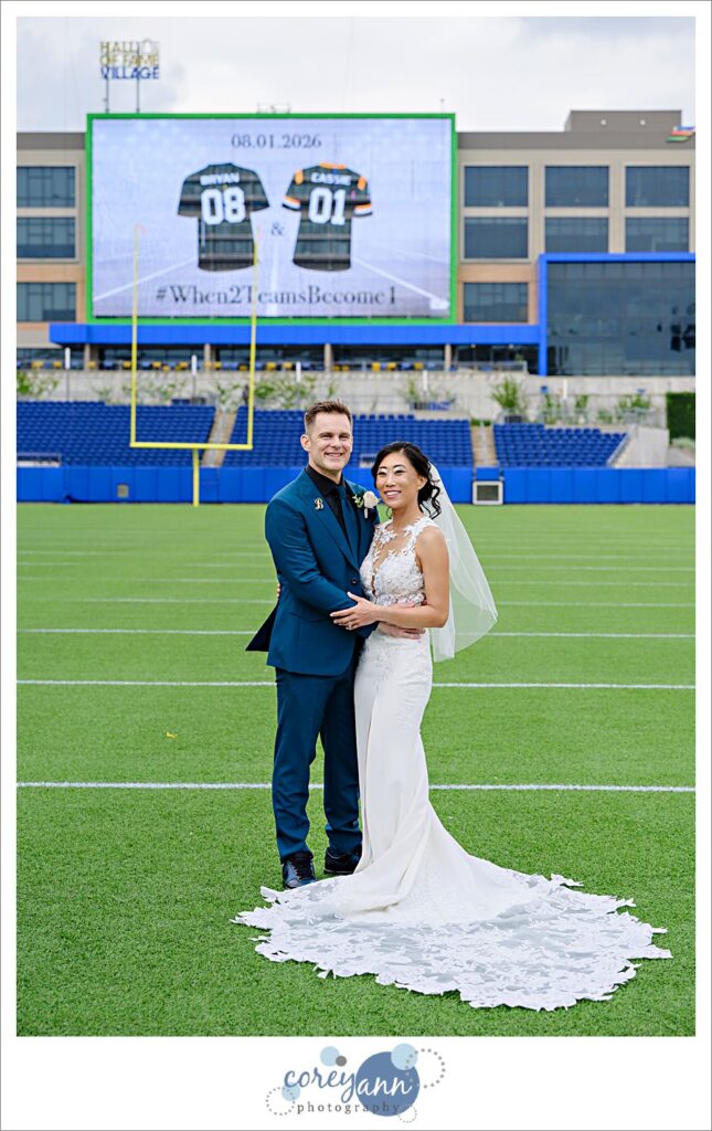 bride and groom posing after wedding on football field at tom benson hall of fame stadium in canton ohio