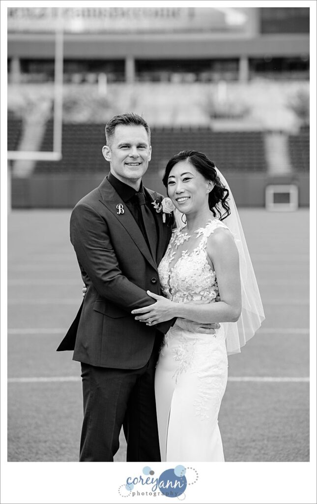 bride and groom posing after wedding on football field at tom benson hall of fame stadium in canton ohio