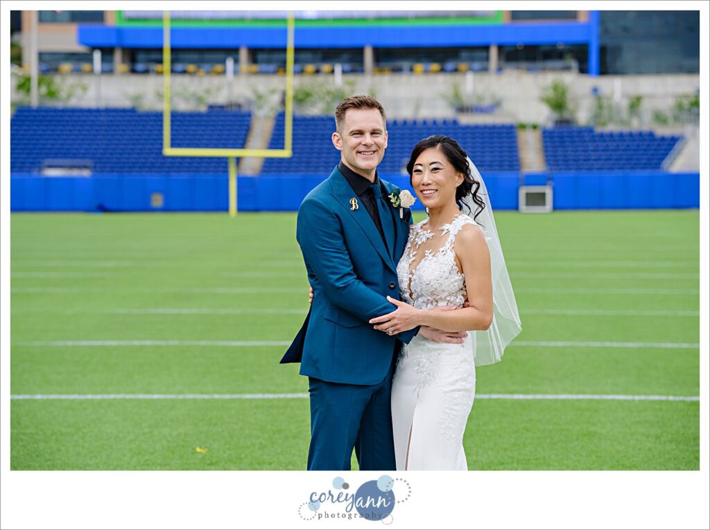 bride and groom posing after wedding on football field at tom benson hall of fame stadium in canton ohio