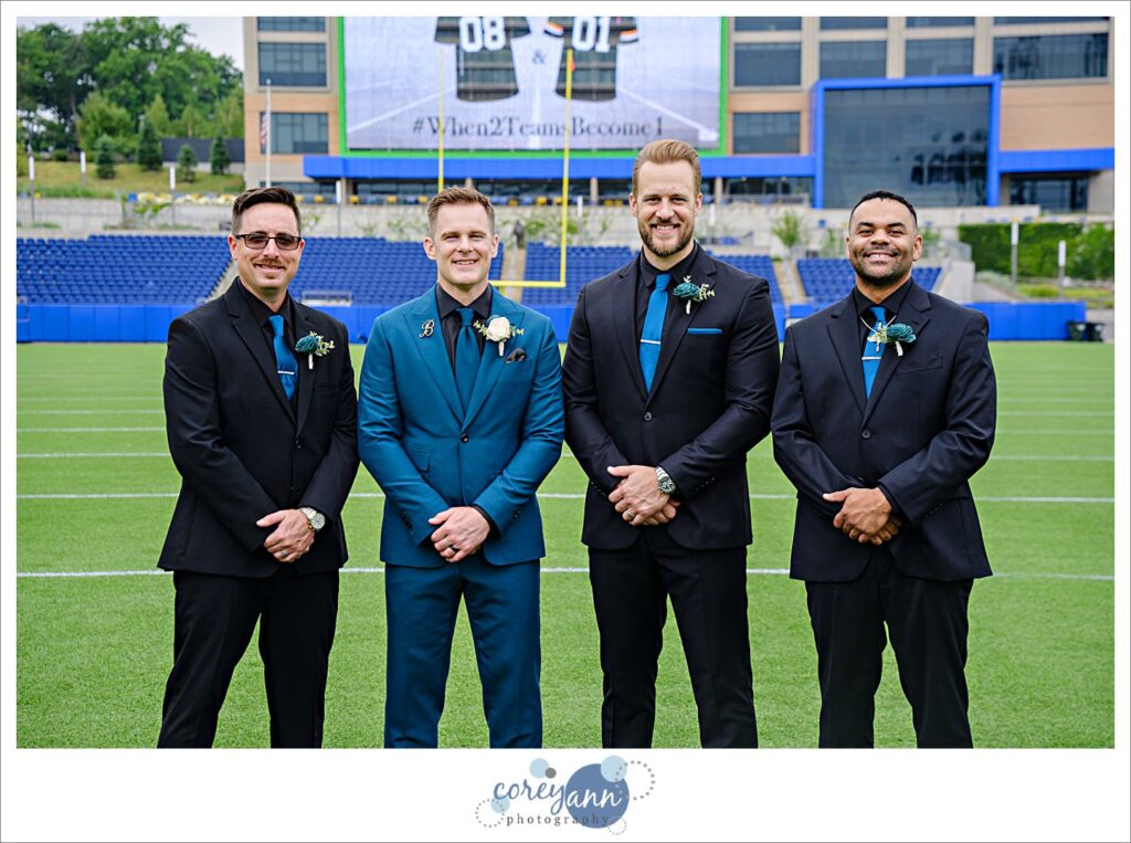 groomsman posing after wedding on football field at tom benson hall of fame stadium in canton ohio