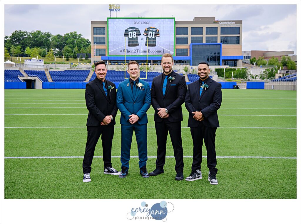 groomsman posing after wedding on football field at tom benson hall of fame stadium in canton ohio