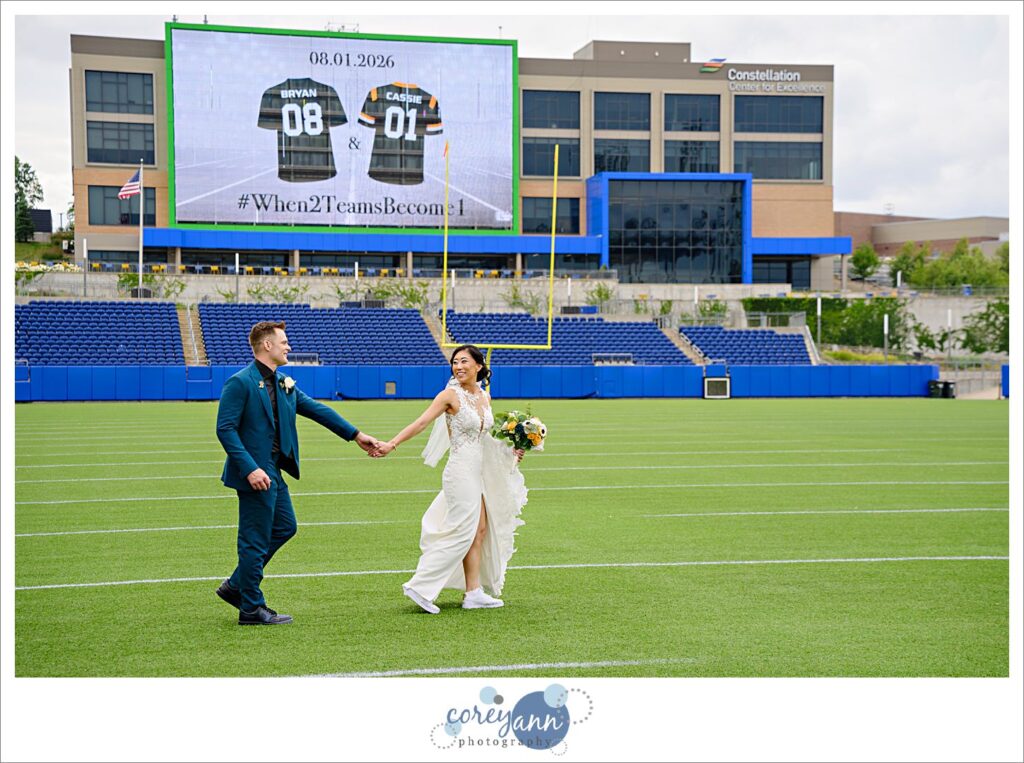 bride and groom posing after wedding on football field at tom benson hall of fame stadium in canton ohio